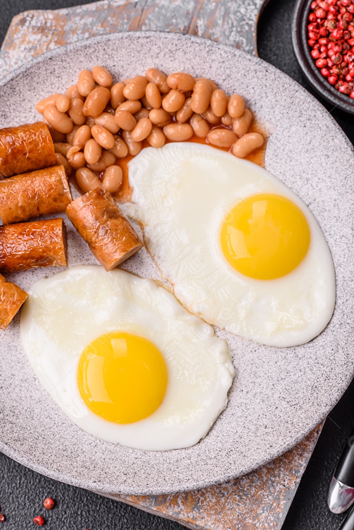 Prato de comida linguiça e ovo frito feijão mesa concreto