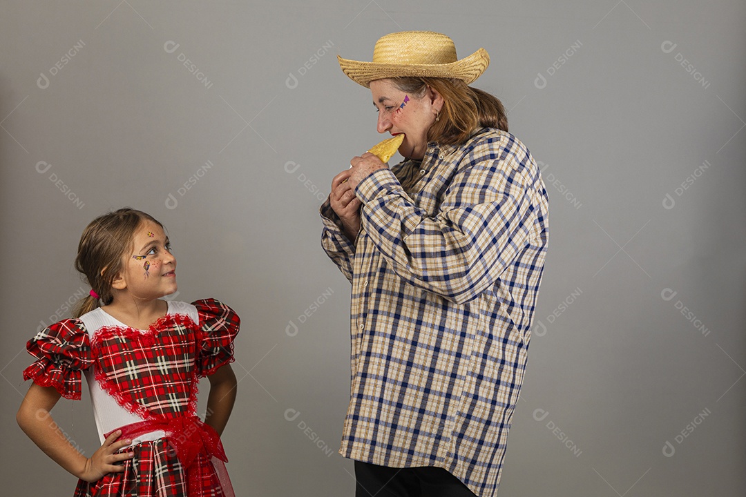 Mulher idosa avó usando roupas típicas de festa junina ao lado de sua neta