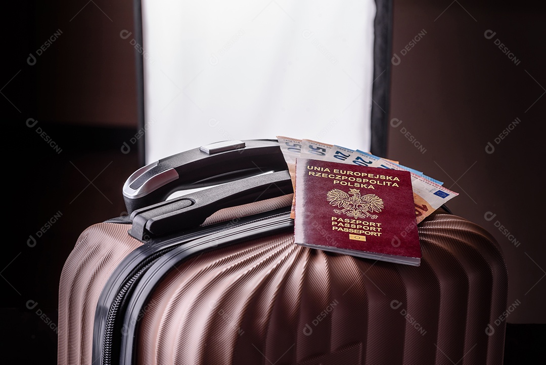 Passaporte sobre uma mala de viagem ao lado de dinheiro