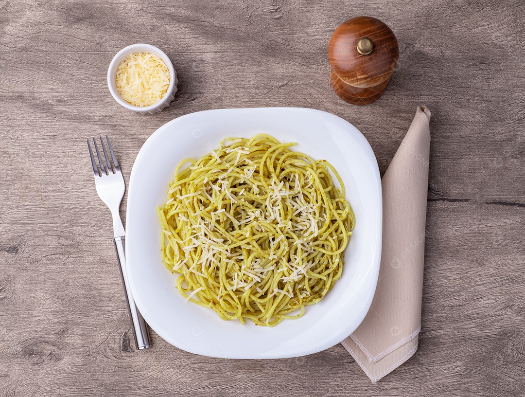 Imagem mostra um prato de massa, possivelmente espaguete ou linguine, com molho pesto e queijo ralado