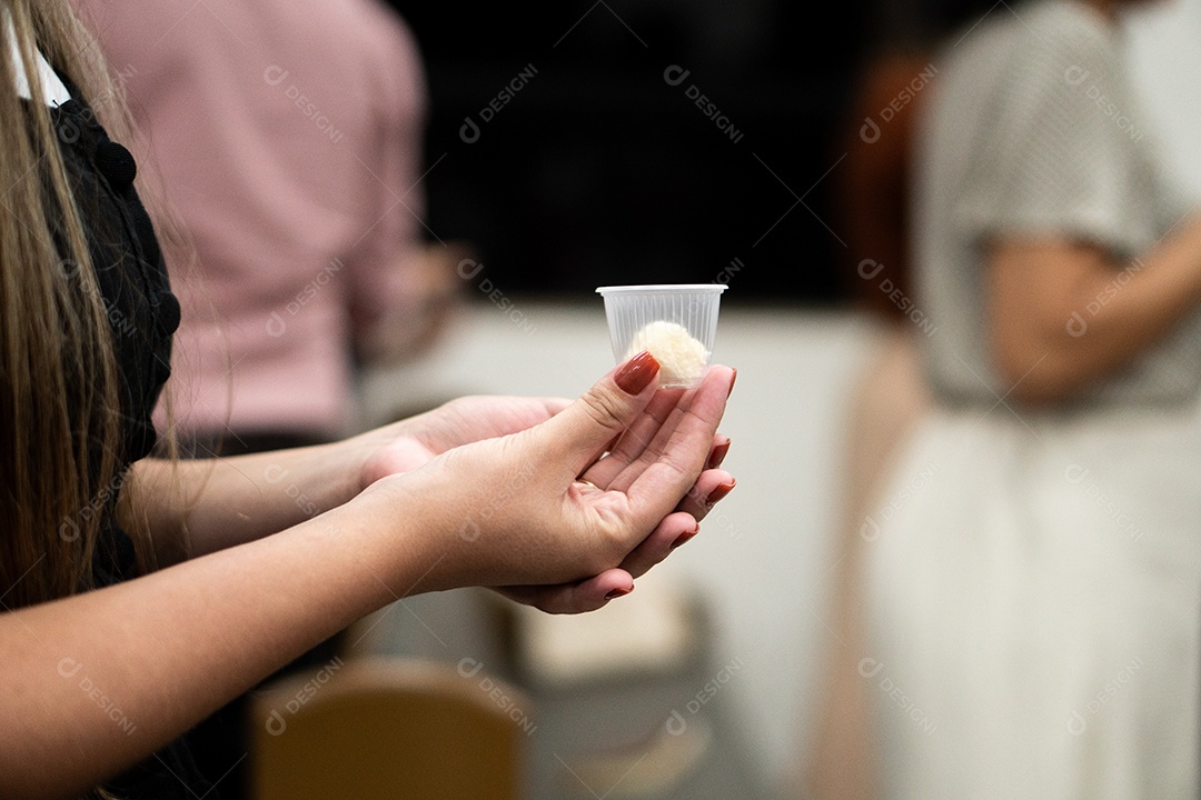 Mão de uma mulher segurando santa ceia sob uma igreja