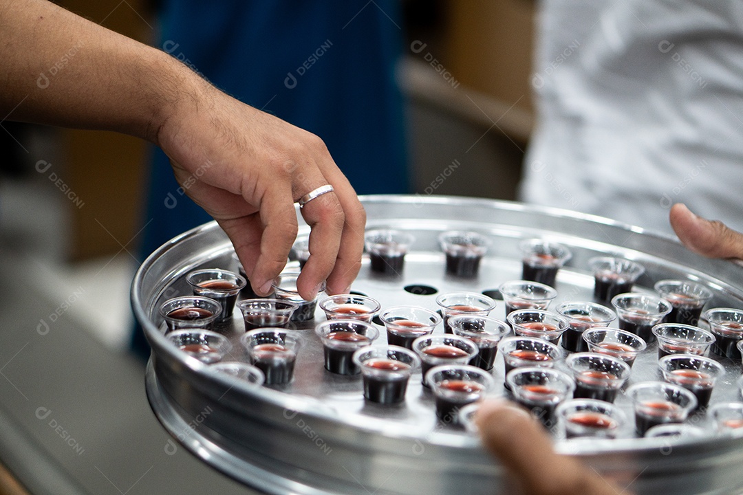 Mão de uma mulher pegando santa ceia em uma bandeija sob uma igreja
