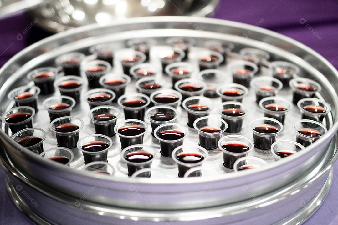 Mão de uma mulher pegando santa ceia em uma bandeija sob uma igreja