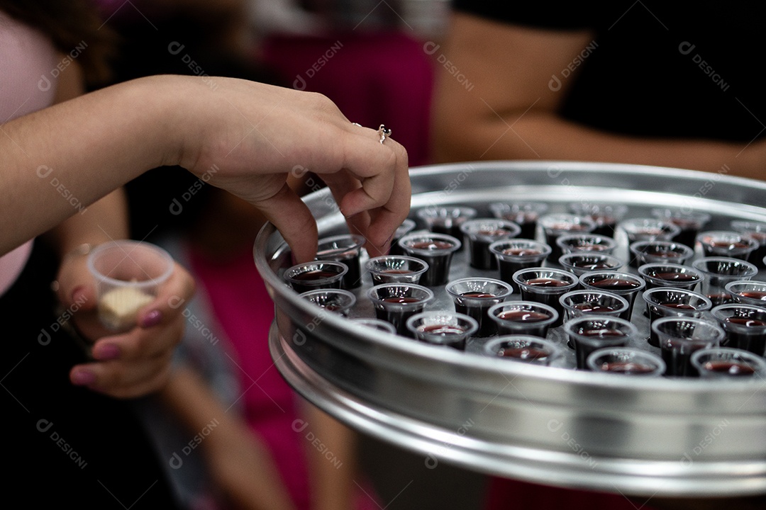 Mão de uma mulher pegando santa ceia em uma bandeija sob uma igreja