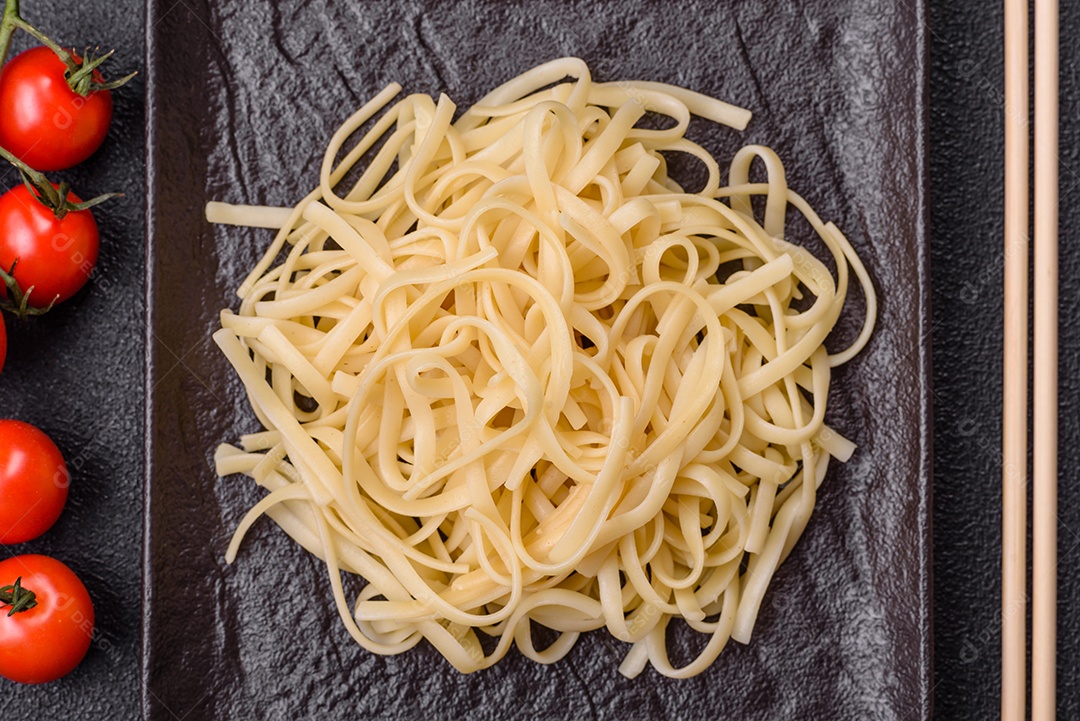 Macarrão de arroz com feijão, carne, molho de tomate, especiarias e ervas em um fundo de concreto escuro