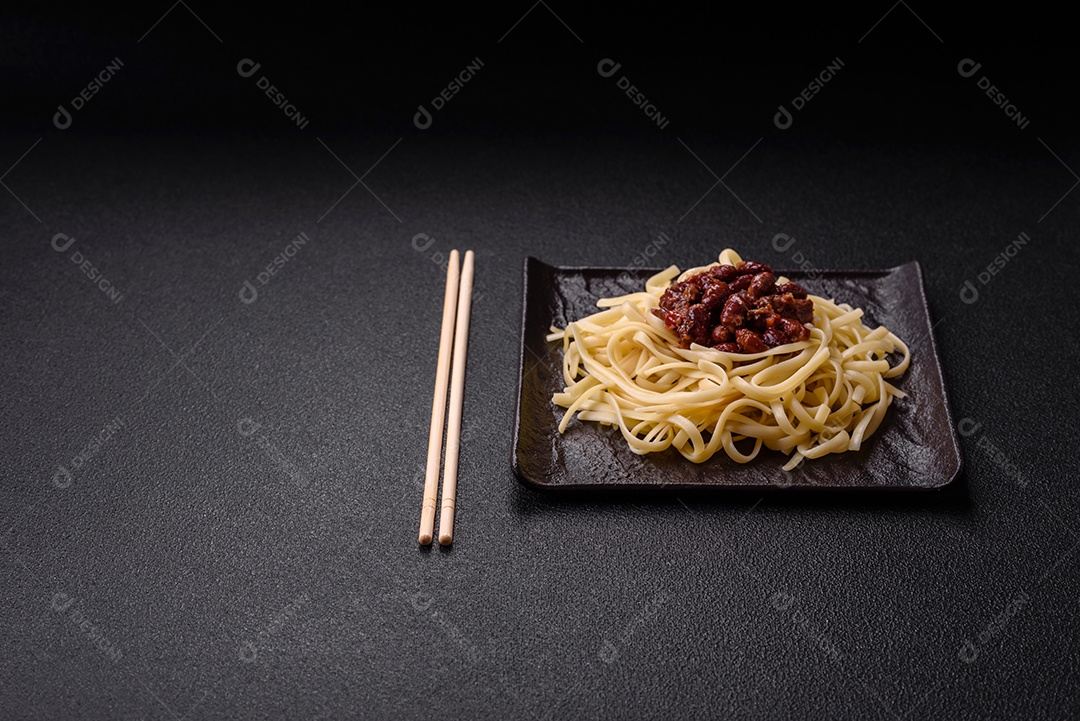 Macarrão de arroz com feijão, carne, molho de tomate, especiarias e ervas em um fundo de concreto escuro
