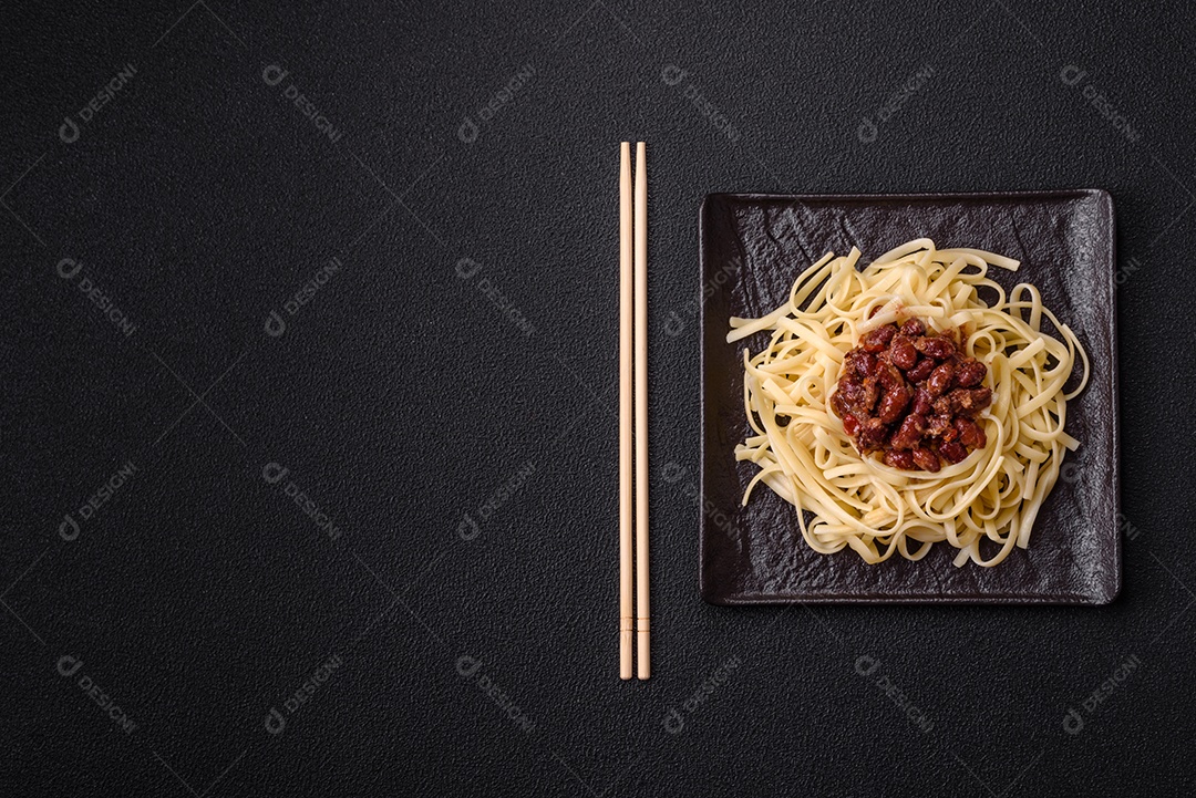 Macarrão de arroz com feijão, carne, molho de tomate, especiarias e ervas em um fundo de concreto escuro