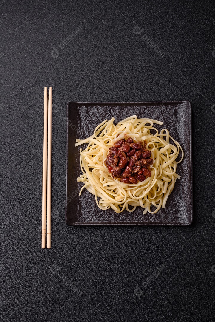 Macarrão de arroz com feijão, carne, molho de tomate, especiarias e ervas em um fundo de concreto escuro