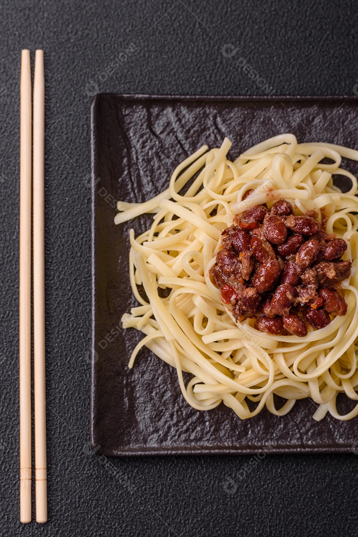 Macarrão de arroz com feijão, carne, molho de tomate, especiarias e ervas em um fundo de concreto escuro