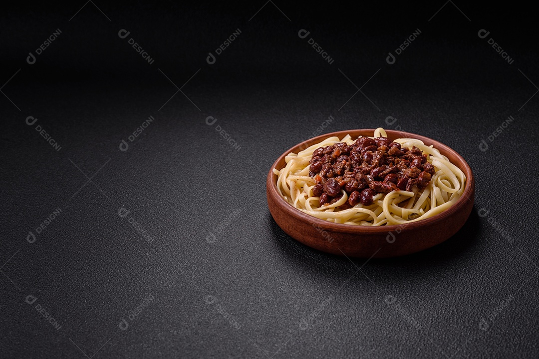 Macarrão de arroz com feijão, carne, molho de tomate, especiarias e ervas em um fundo de concreto escuro