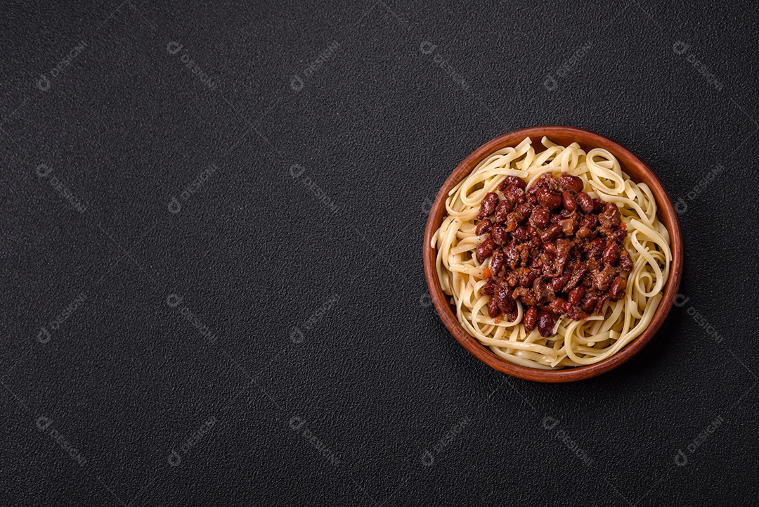 Macarrão de arroz com feijão, carne, molho de tomate, especiarias e ervas em um fundo de concreto escuro