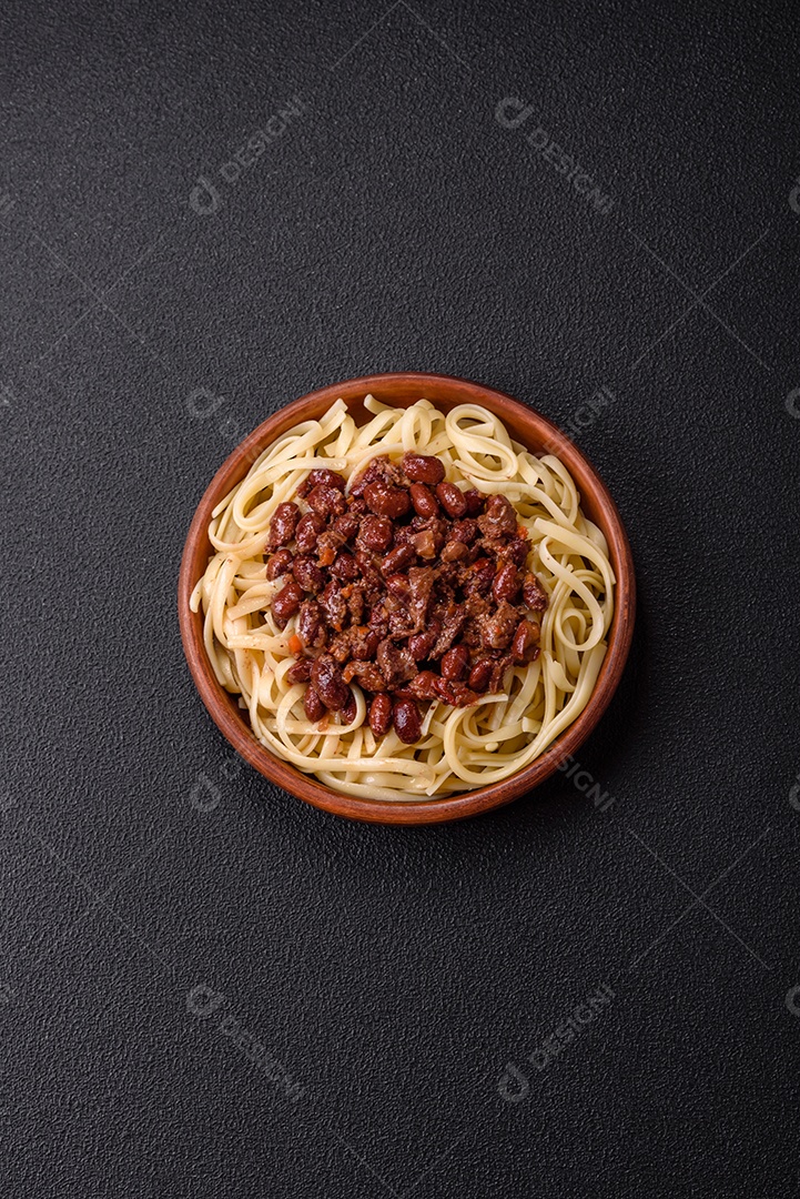 Macarrão de arroz com feijão, carne, molho de tomate, especiarias e ervas em um fundo de concreto escuro