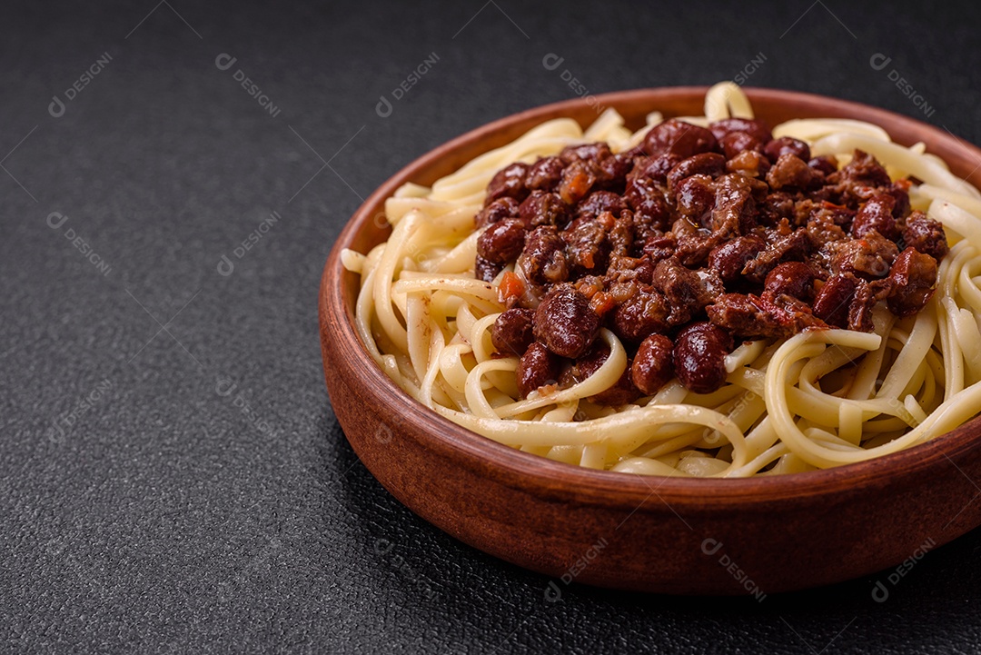 Macarrão de arroz com feijão, carne, molho de tomate, especiarias e ervas em um fundo de concreto escuro