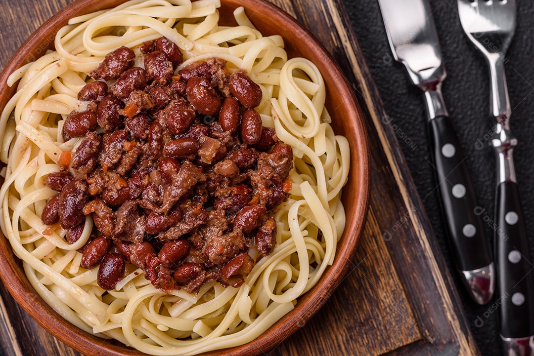 Macarrão de arroz com feijão, carne, molho de tomate, especiarias e ervas em um fundo de concreto escuro