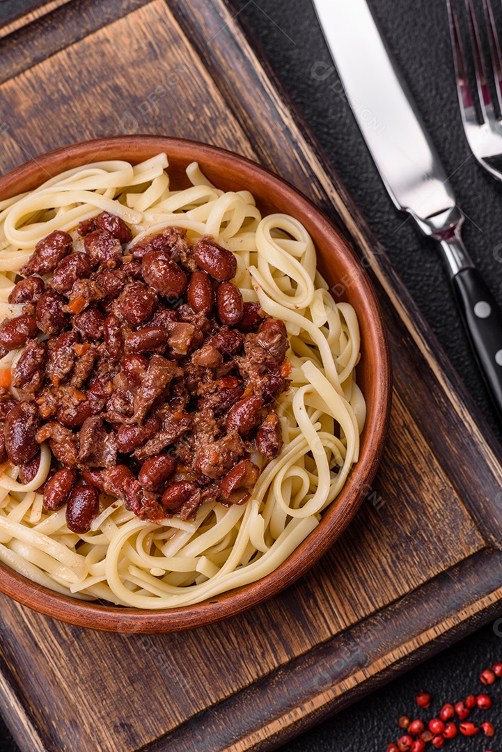 Macarrão de arroz com feijão, carne, molho de tomate, especiarias e ervas em um fundo de concreto escuro