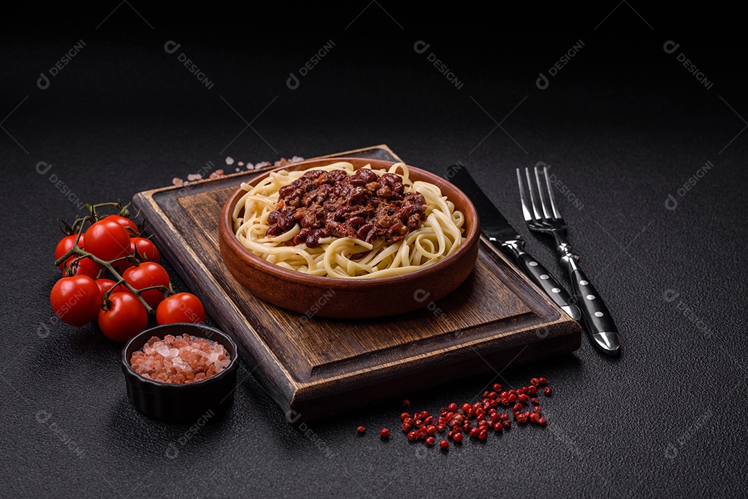 Macarrão de arroz com feijão, carne, molho de tomate, especiarias e ervas em um fundo de concreto escuro