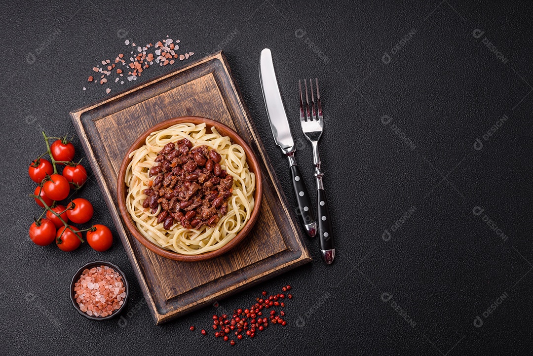 Macarrão de arroz com feijão, carne, molho de tomate, especiarias e ervas em um fundo de concreto escuro