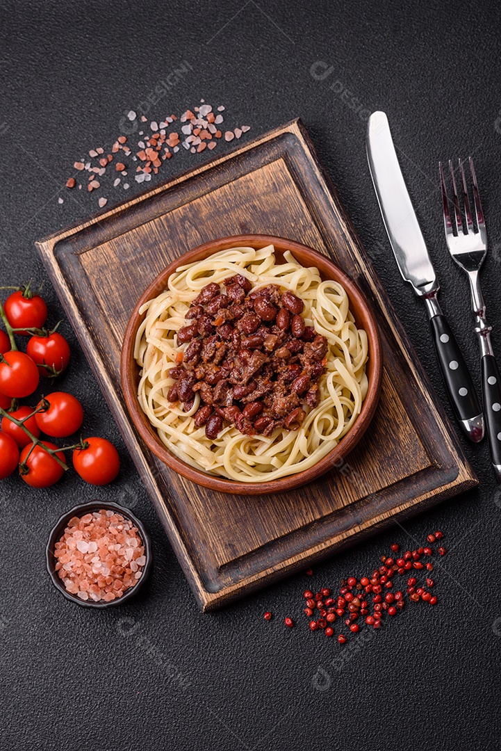 Macarrão de arroz com feijão, carne, molho de tomate, especiarias e ervas em um fundo de concreto escuro