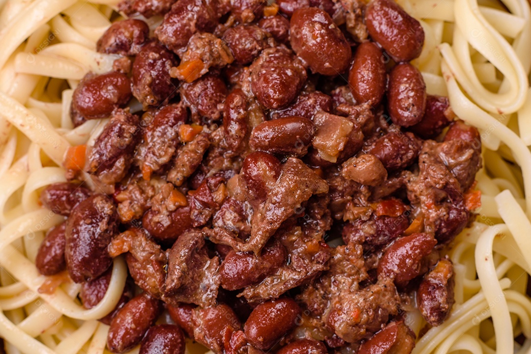 Macarrão de arroz com feijão, carne, molho de tomate, especiarias e ervas em um fundo de concreto escuro