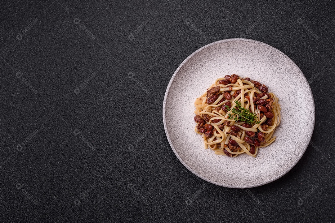 Macarrão de arroz com feijão, carne, molho de tomate, especiarias e ervas em um fundo de concreto escuro