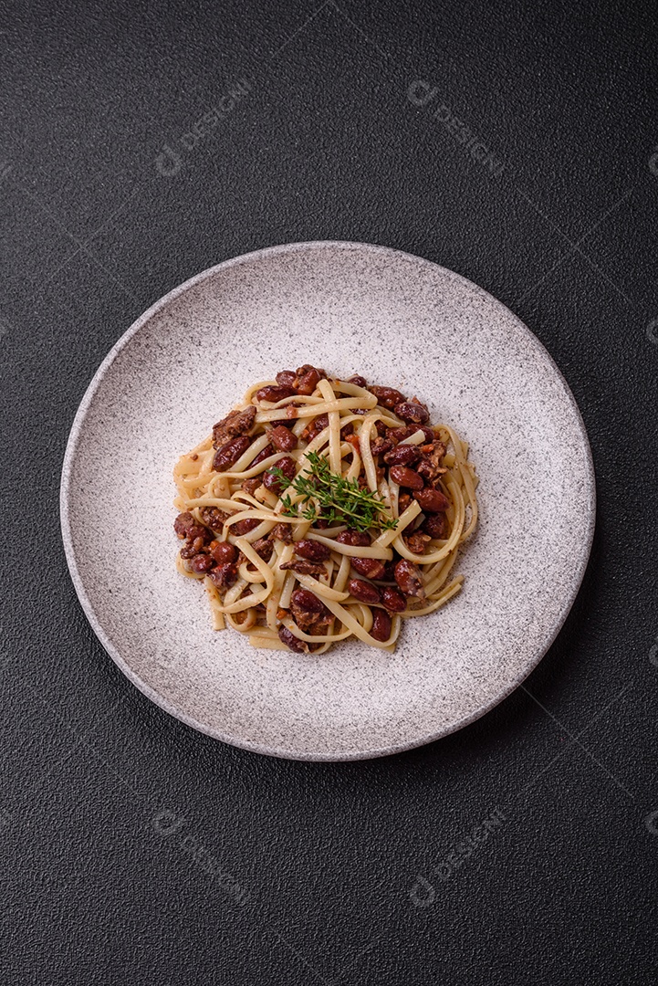 Macarrão de arroz com feijão, carne, molho de tomate, especiarias e ervas em um fundo de concreto escuro