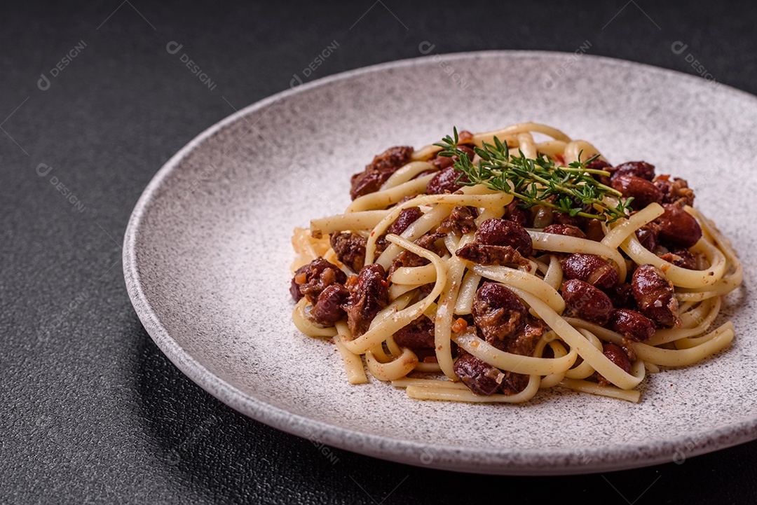 Macarrão de arroz com feijão, carne, molho de tomate, especiarias e ervas em um fundo de concreto escuro