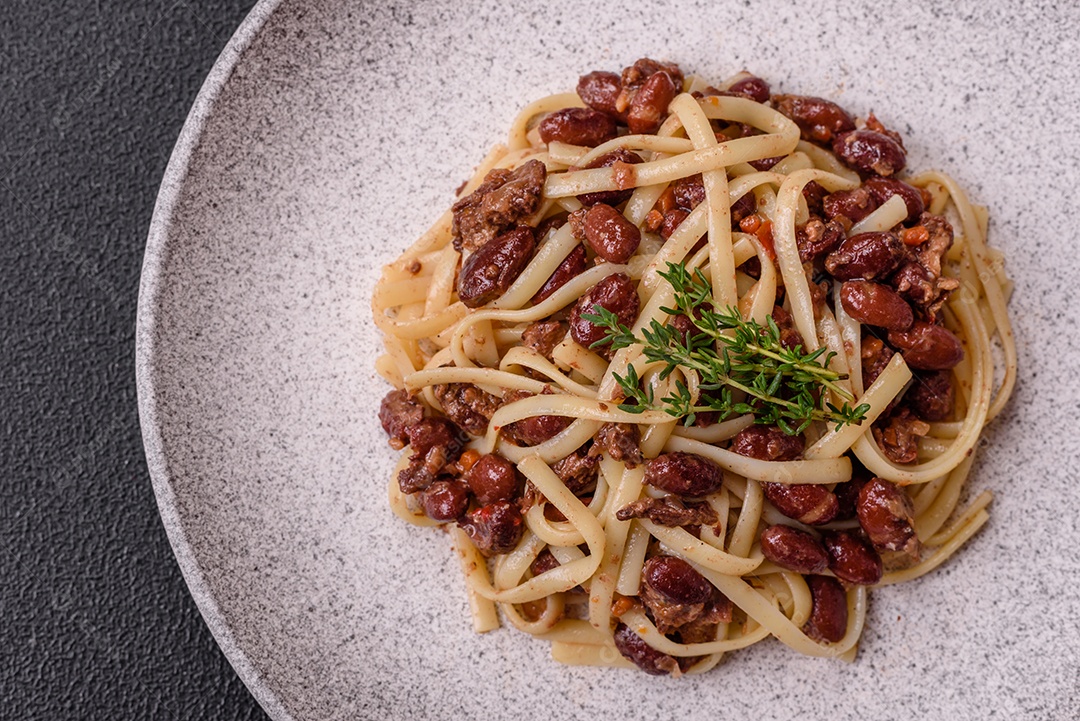 Macarrão de arroz com feijão, carne, molho de tomate, especiarias e ervas em um fundo de concreto escuro