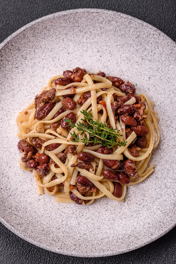 Macarrão de arroz com feijão, carne, molho de tomate, especiarias e ervas em um fundo de concreto escuro