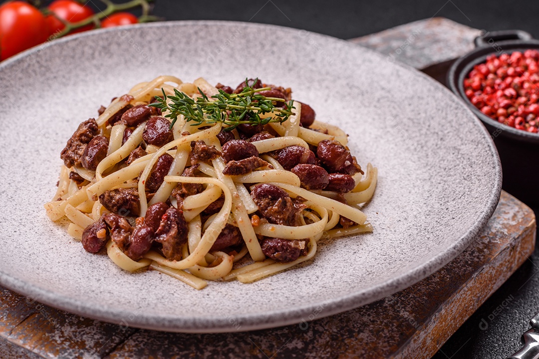Macarrão de arroz com feijão, carne, molho de tomate, especiarias e ervas em um fundo de concreto escuro