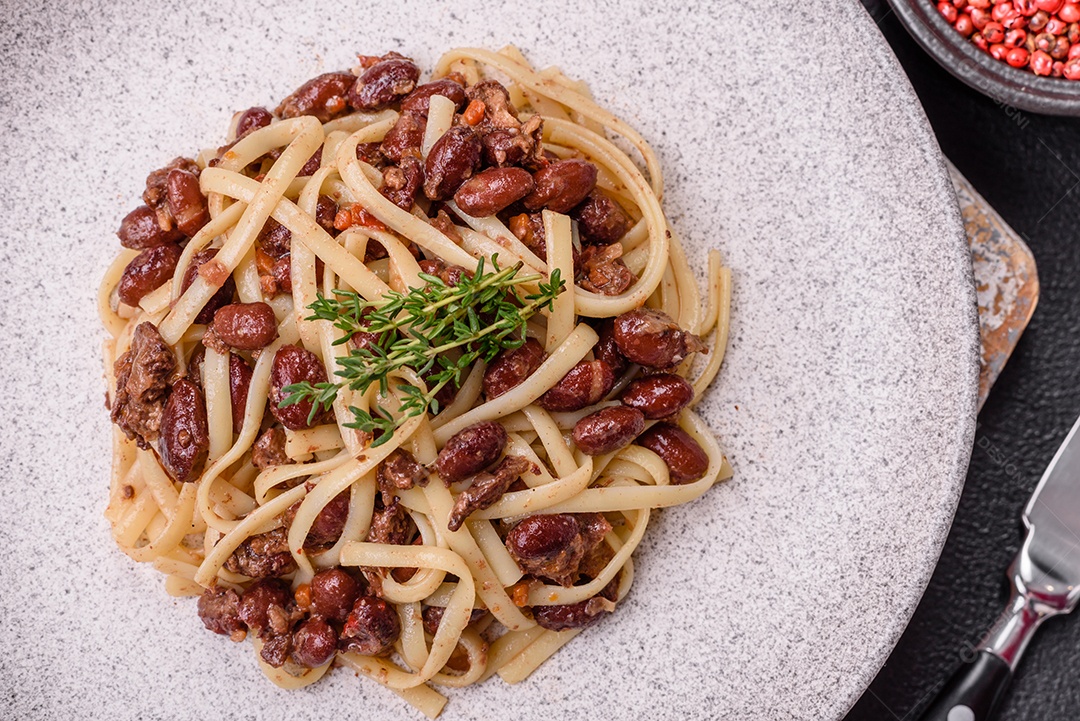 Macarrão de arroz com feijão, carne, molho de tomate, especiarias e ervas em um fundo de concreto escuro