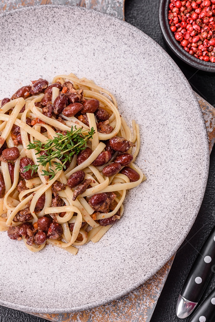 Macarrão de arroz com feijão, carne, molho de tomate, especiarias e ervas em um fundo de concreto escuro