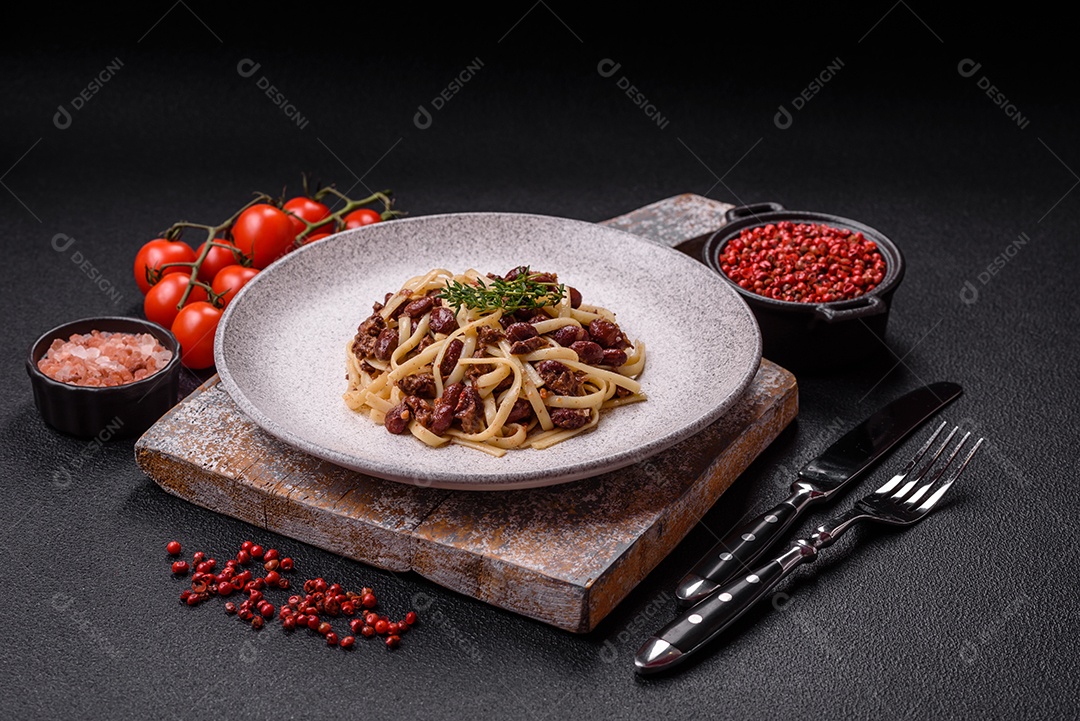 Macarrão de arroz com feijão, carne, molho de tomate, especiarias e ervas em um fundo de concreto escuro