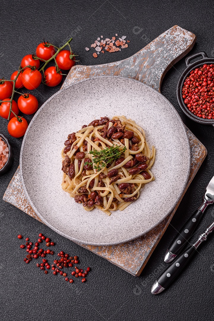 Macarrão de arroz com feijão, carne, molho de tomate, especiarias e ervas em um fundo de concreto escuro