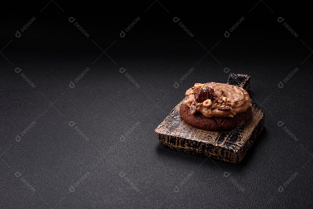 Biscoitos doces de aveia com creme de manteiga ou manteiga de amendoim e nozes em fundo de concreto escuro