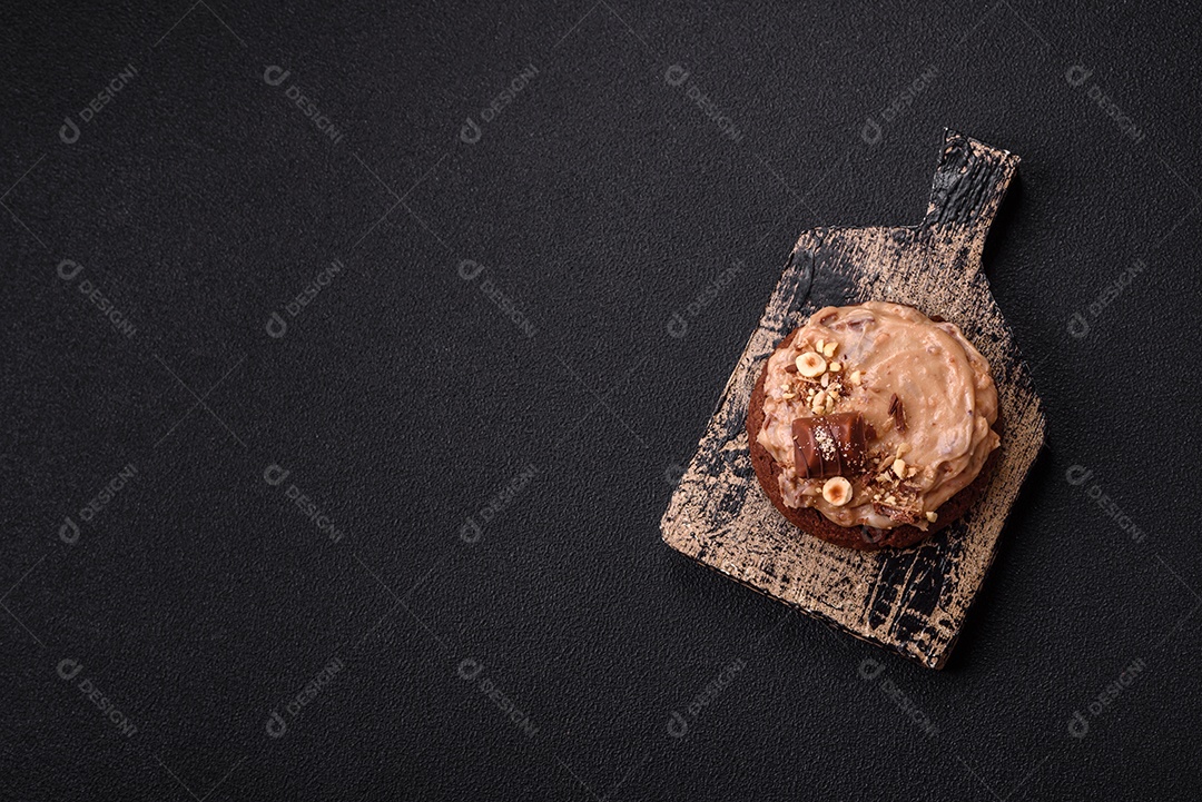 Biscoitos doces de aveia com creme de manteiga ou manteiga de amendoim e nozes em fundo de concreto escuro