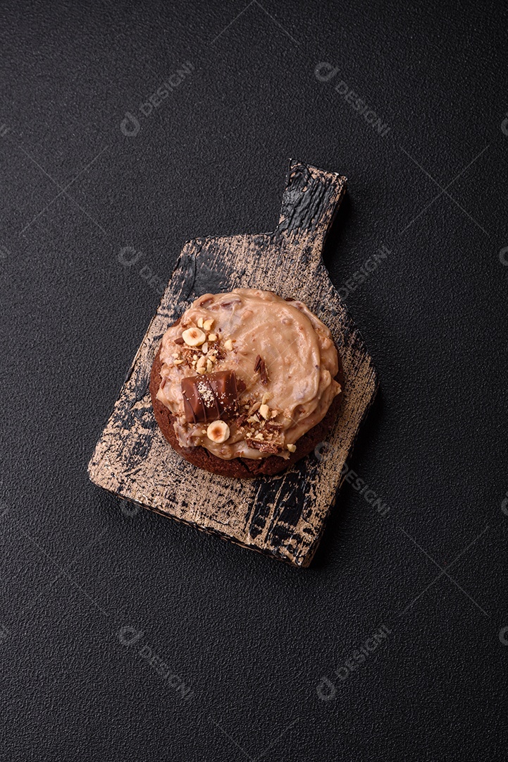 Biscoitos doces de aveia com creme de manteiga ou manteiga de amendoim e nozes em fundo de concreto escuro