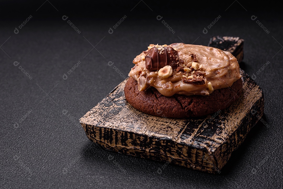 Biscoitos doces de aveia com creme de manteiga ou manteiga de amendoim e nozes em fundo de concreto escuro