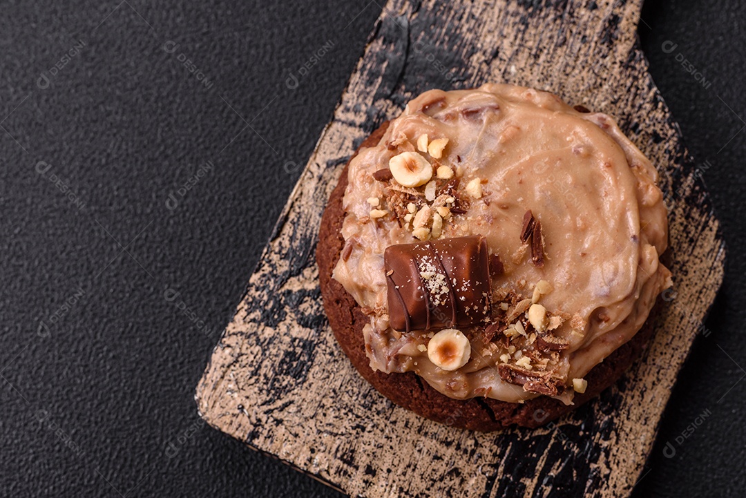 Biscoitos doces de aveia com creme de manteiga ou manteiga de amendoim e nozes em fundo de concreto escuro