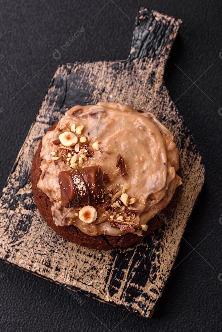 Biscoitos doces de aveia com creme de manteiga ou manteiga de amendoim e nozes em fundo de concreto escuro