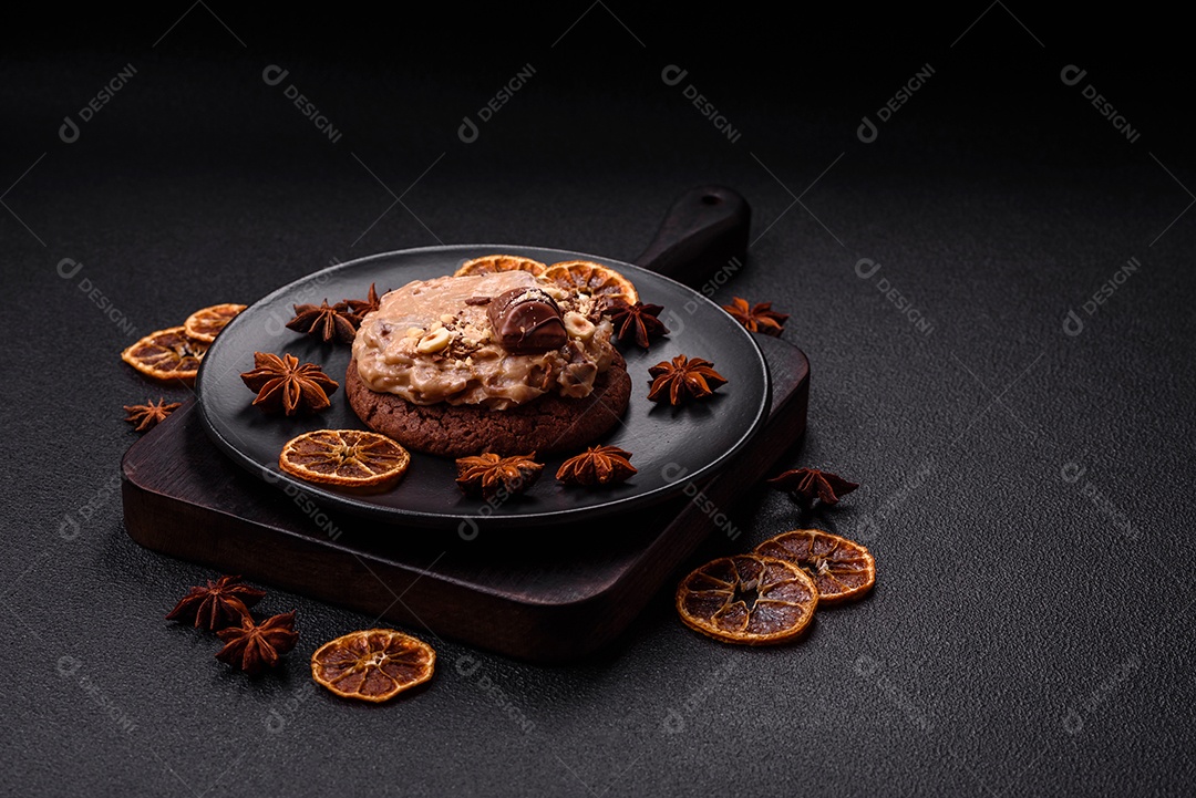 Biscoitos doces de aveia com creme de manteiga ou manteiga de amendoim e nozes em fundo de concreto escur