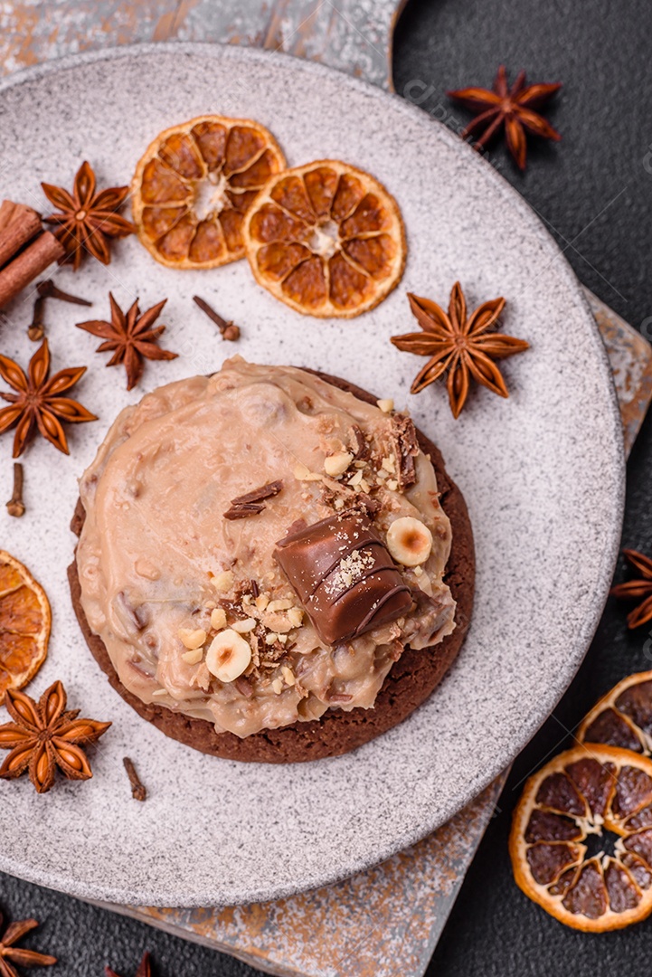 Biscoitos doces de aveia com creme de manteiga ou manteiga de amendoim e nozes em fundo de concreto escuro
