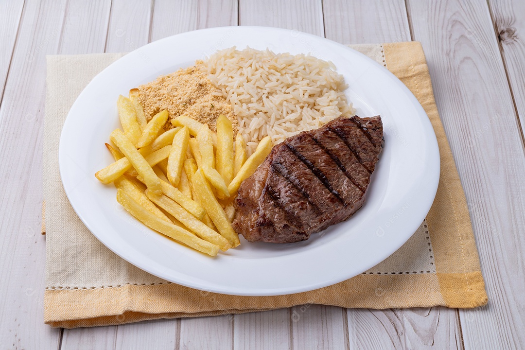 A imagem mostra um prato de comida que inclui um bife, batatas fritas, arroz e feijão