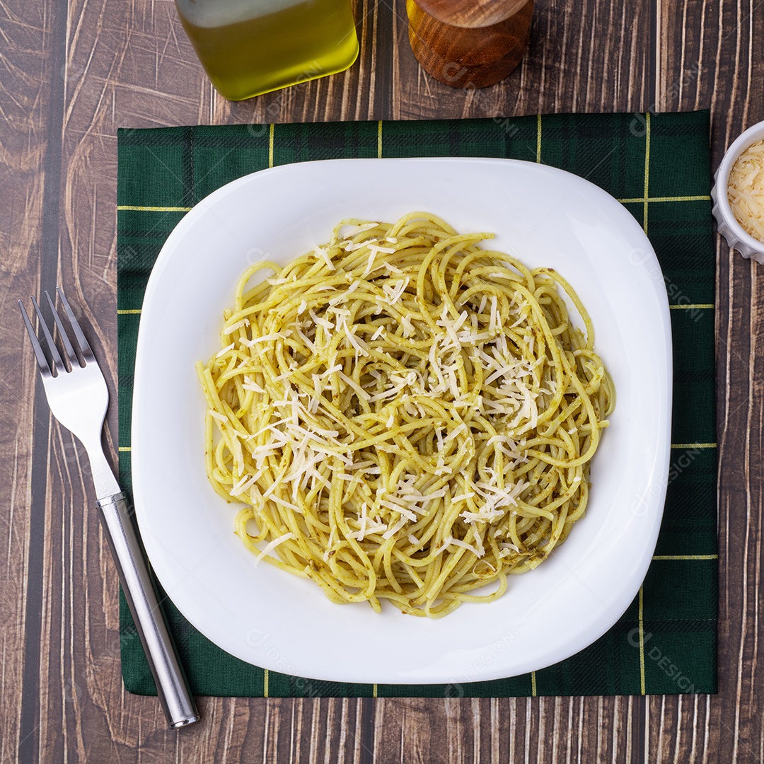 A imagem mostra um prato de espaguete com molho pesto, polvilhado com queijo ralado