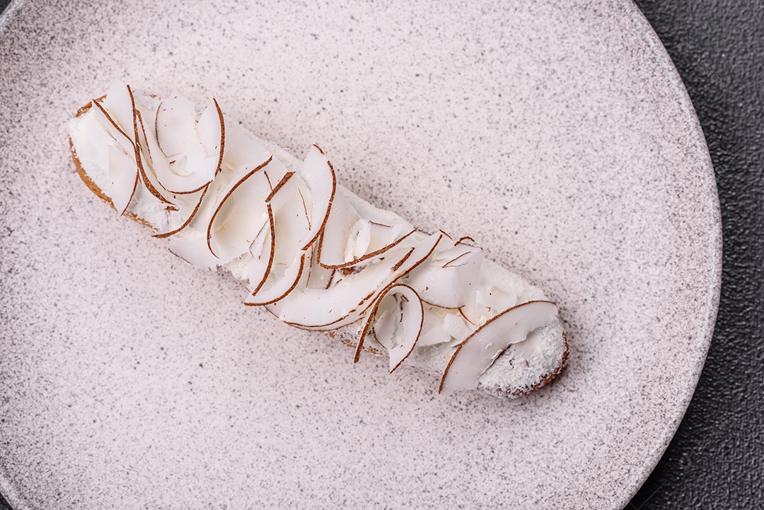 Éclair doce com creme decorado com fatias de coco