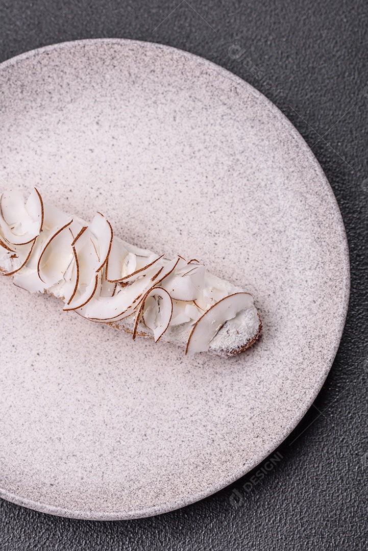 Éclair doce com creme decorado com fatias de coco