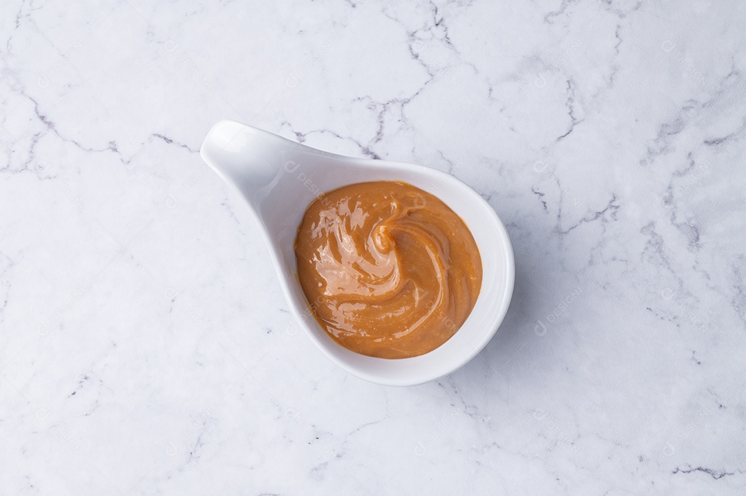 Retrato mostra uma porção de doce de leite em uma pequena tigela branca.