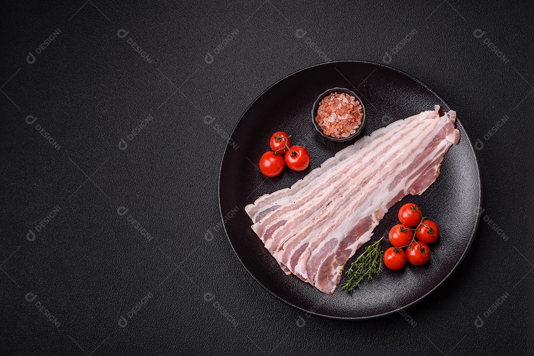 Imagem mostra fatias de bacon cru, acompanhadas de tomates cereja e sal rosa.