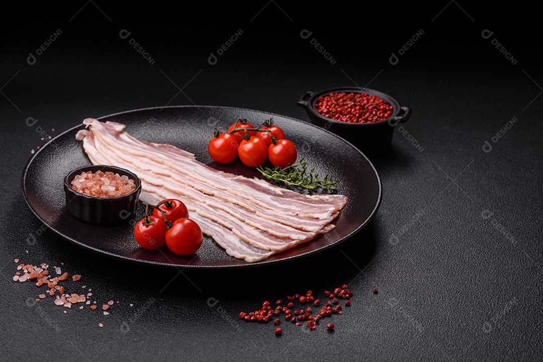 Imagem mostra fatias de bacon cru, acompanhadas de tomates cereja e sal rosa.