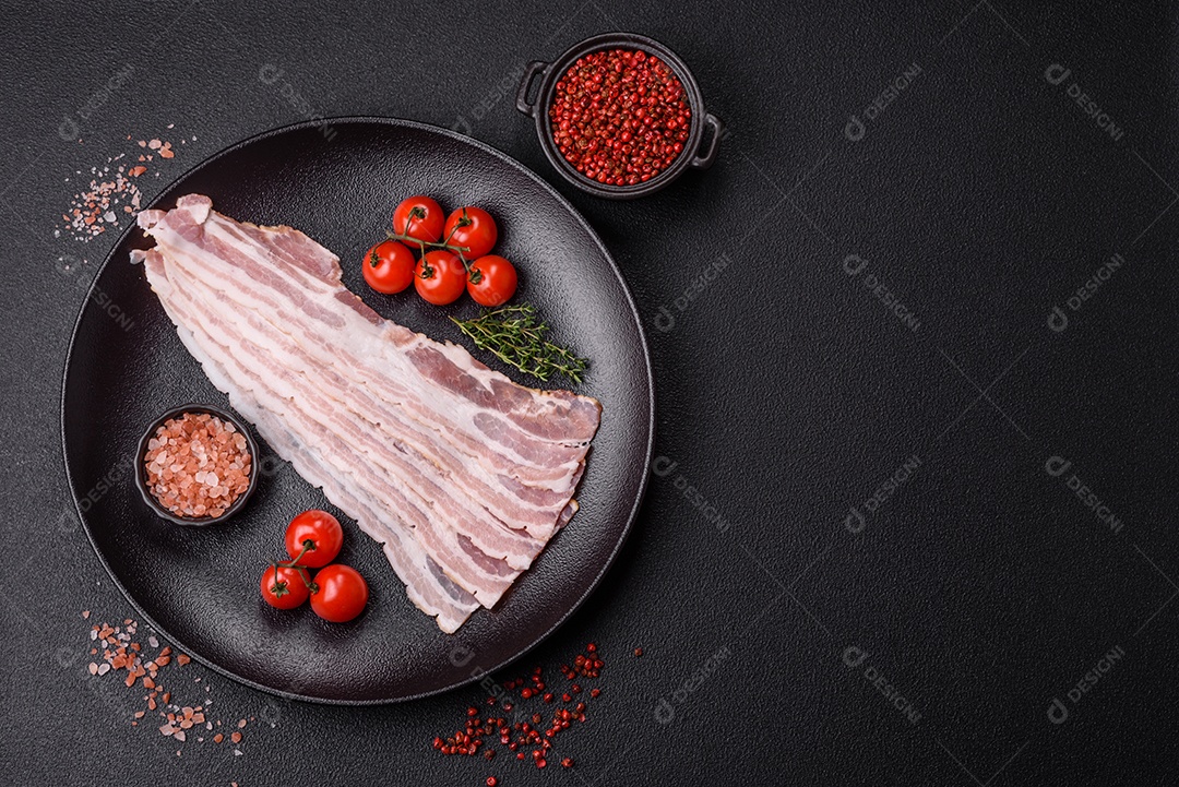 Imagem mostra fatias de bacon cru, acompanhadas de tomates cereja e sal rosa.