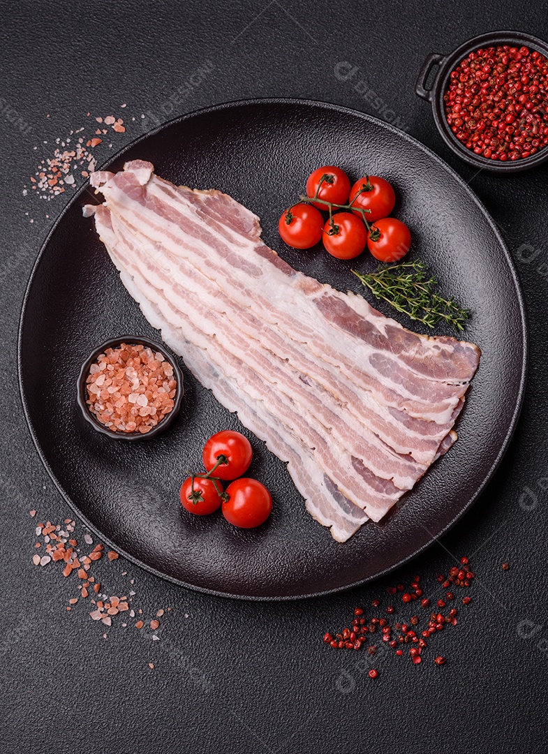 Imagem mostra fatias de bacon cru, acompanhadas de tomates cereja e sal rosa.